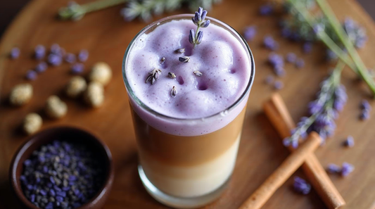 Iced lavender cream chai with vibrant purple foam on top, amber chai concentrate in the middle, and milk on the bottom, garnished with fresh lavender buds and cinnamon